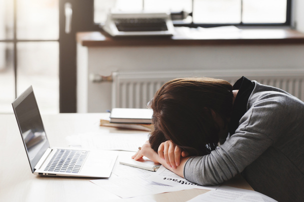 Young tired woman sleeping at office desk - Foto, imagen