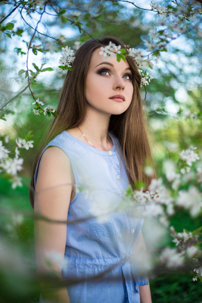 portrait of young woman dreaming in blooming cherry garden - Foto, Imagen
