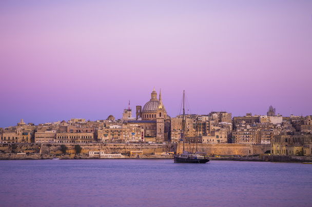 Ciudad de La Valeta al atardecer con la Catedral de San Pablo y velero y cielo púrpura, Malta
 - Foto, Imagen