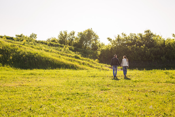 вид сзади пары, держащейся за руки, идущей осенью по сельской местности
 - Фото, изображение