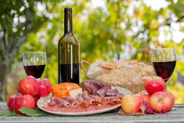 Ambiente de vida campestre con vino, frutas, queso y carne. Exterior
 - Foto, imagen