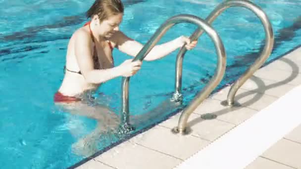 A lady in red bikini walks out of the pool - Кадри, відео