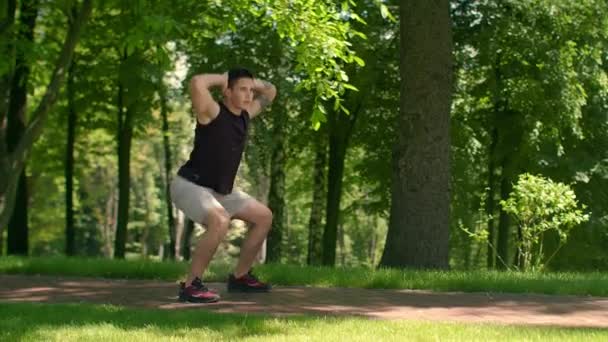 Outdoor-Fitness. Fitnessmann trainiert im Park. Mann macht Kniebeugen. Fitter Mann kauert - Filmmaterial, Video