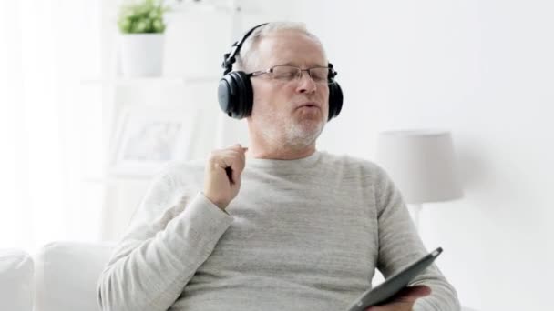 senior man with tablet pc and headphones at home 90 - Felvétel, videó