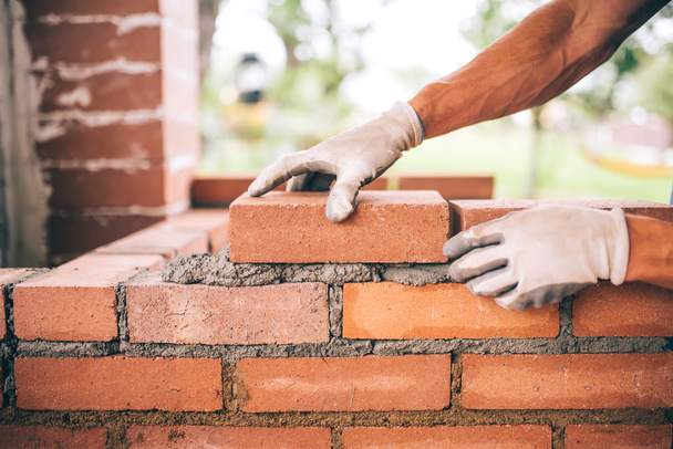 professional construction worker laying bricks and building barbecue in industrial site. Detail of hand adjusting bricks - Foto, Bild