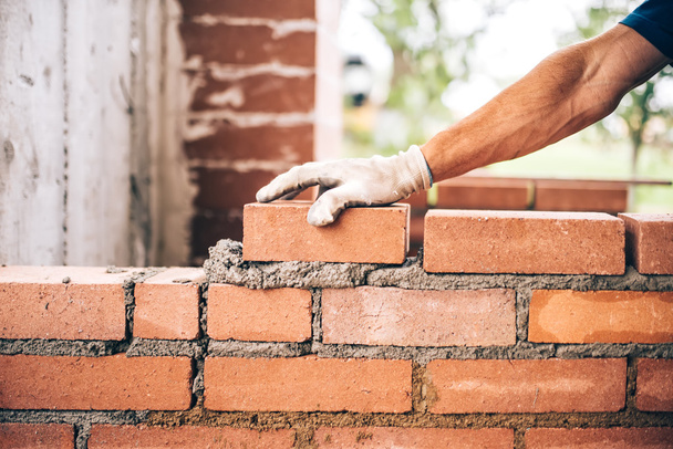 industrial bricklayer worker placing bricks on cement while building exterior walls, industry details - Foto, immagini