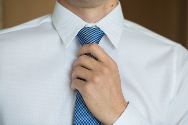 Businessman in blue suit tying the necktie - Zdjęcie, obraz