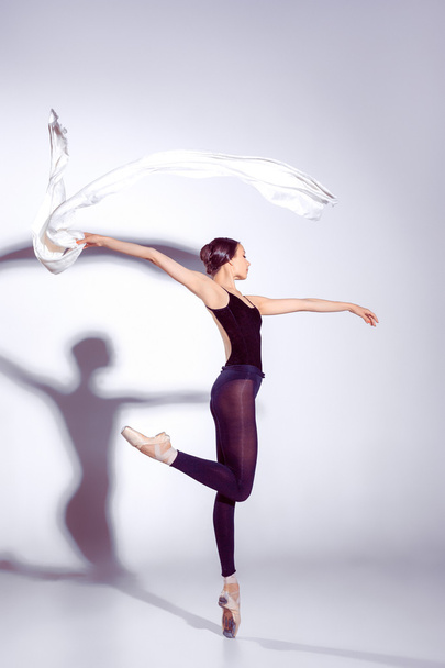 Bailarina en traje negro posando en los dedos de los pies, fondo del estudio
. - Foto, Imagen