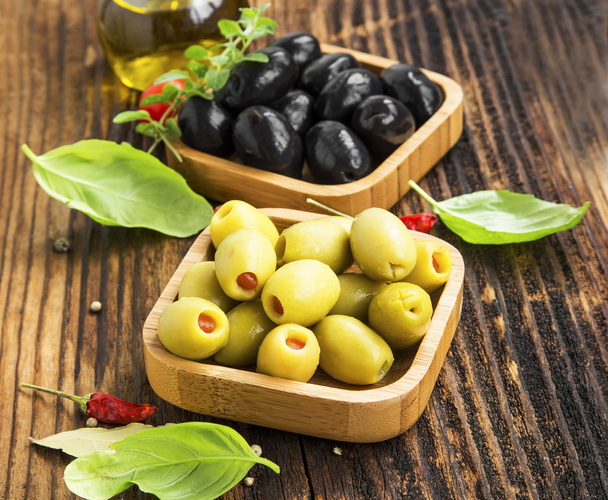 Organické zelené a černé olivy v dřevěných misek s kořením - Fotografie, Obrázek