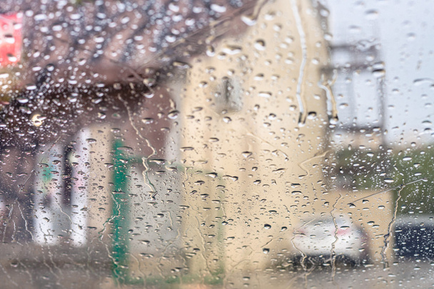 eső csepeg a szélvédő és homályos ház - Fotó, kép