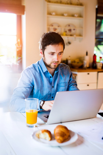 Man sitting at desk working from home on laptop - Foto, Bild