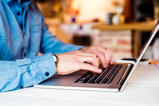 Неузнаваемый человек работает из дома на ноутбуке
 - Фото, изображение