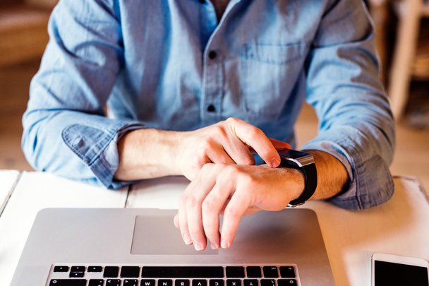 Homem trabalhando em casa no laptop, vestindo smartwatch
 - Foto, Imagem
