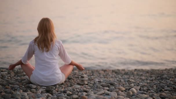 νεαρή γυναίκα την πρακτική της γιόγκα στην παραλία το ηλιοβασίλεμα. ήρεμη θάλασσα - Πλάνα, βίντεο