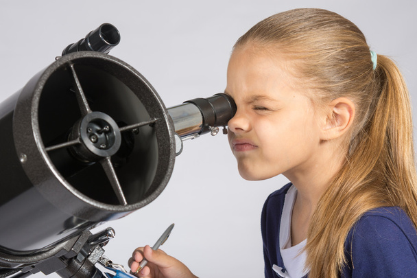 De jonge astronoom kijkt door het oculair van de telescoop en record resultaten - Foto, afbeelding