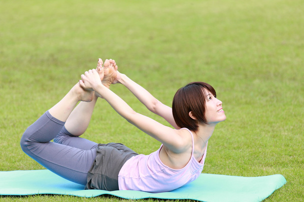 Japanese woman outside doing yoga bow pose - Foto, immagini