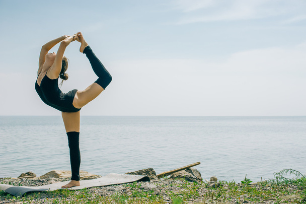 young woman is engaged in meditation, stretching, yoga on the beach background - Фото, зображення