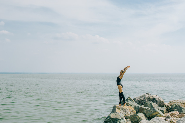 jovem está envolvida em meditação, alongamento, ioga no fundo da praia
 - Foto, Imagem