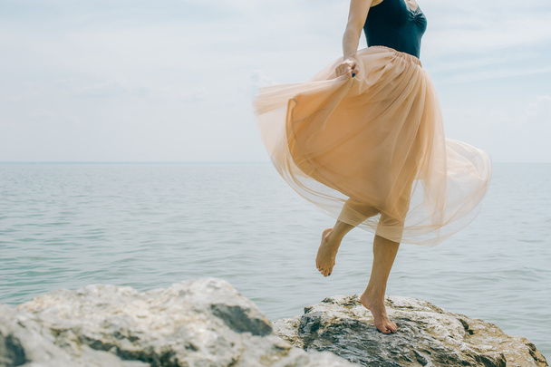 girl dancing on the rocks on the shore - Foto, Imagem