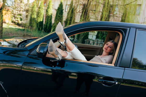 Mädchen im teuren Auto mit Beinen  - Foto, Bild