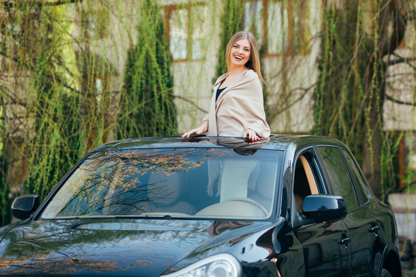 Picture of cheerful young woman wearing sunglasses and raised hands on the sunroof  - Foto, Bild