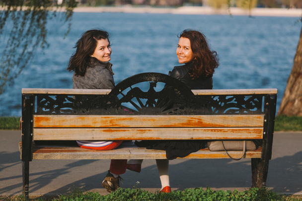 Cute girls sitting on a wooden bench, smiling - Valokuva, kuva