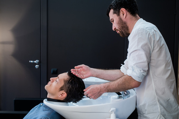 Haarstylist Kapper wassen klant Hair - jonge Man ontspannen In het kapsalon Beauty - Foto, afbeelding