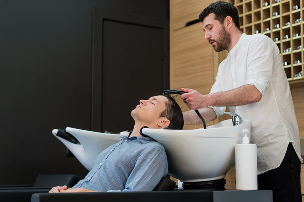 Young man at hairdresser salon getting his hair washed - Photo, Image