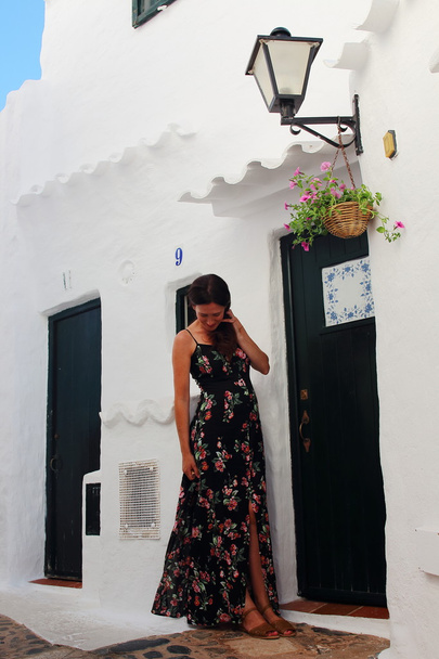 Młoda piękna ciężarna kobieta relaksuje się w cudownych białych murowanych ulicach śródziemnomorskiej wioski na wyspie Menorca, Hiszpania - Zdjęcie, obraz