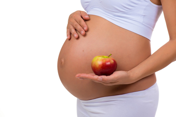 Close-up of pregnant belly and apple. Vitamins and healthy food during pregnancy - Valokuva, kuva