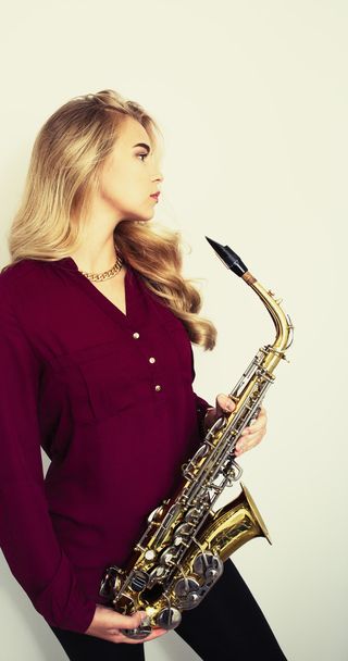 Profile of beautiful young woman holding saxophone - Foto, Bild