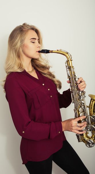 Profile of beautiful young woman playing saxophone - Foto, imagen