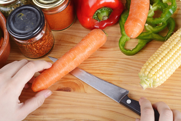 Person cutting a carrot with vegetables and spices. - Photo, Image