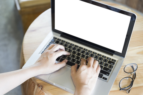 woman's hand on computer notebook with eyeglasses on wooden desk - Foto, Bild