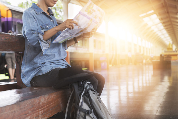 женщина держит карту с рюкзаком на вокзале
 - Фото, изображение