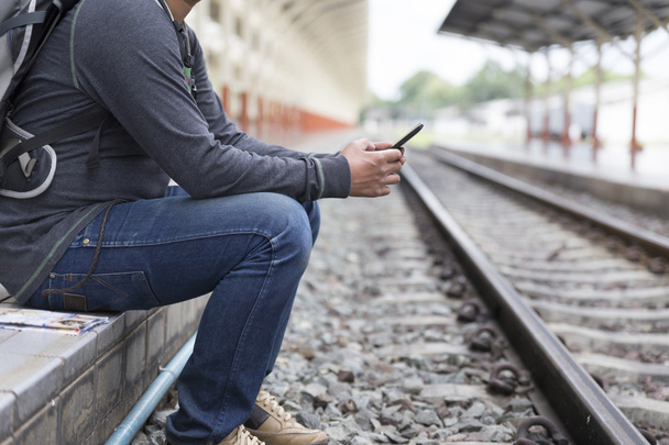man holding smartphone at train station - Foto, Bild