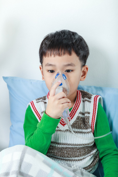 アジアの子供は、喘息の治療のためマスクの蒸気吸入器を保持しています。.  - 写真・画像