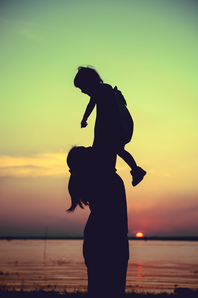 Silhouette di madre e figlio godendo la vista sul lungofiume
.  - Foto, immagini
