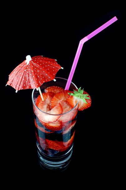 Longdrinkglas mit Sommerfrüchten, einem Strohhalm und einem Cocktailschirm - Foto, Bild