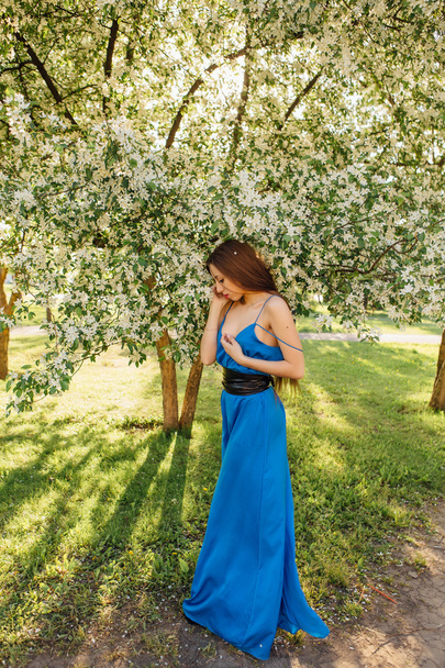 Beautiful young woman standing near the apple tree. - Φωτογραφία, εικόνα