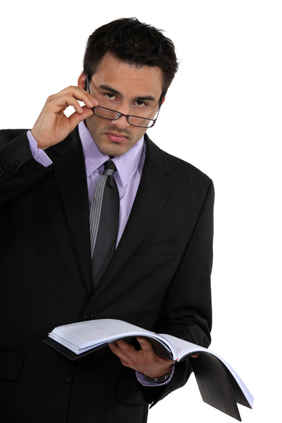 Businessman peering over his glasses and holding his agenda - Foto, immagini
