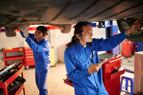 Mechaniker untersuchen Auto in Garage - Foto, Bild