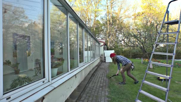 Chica limpieza de ventanas de invernadero con una presión de chorro de agua
. - Imágenes, Vídeo