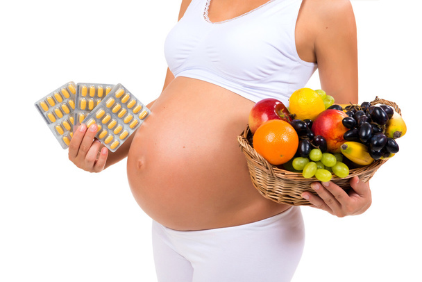 Healthy pregnancy: pills or fruit? Close-up of a pregnant belly - Foto, Imagem