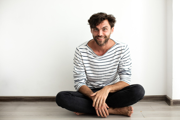 Handsome man in stripes sitting down on the floor - Foto, afbeelding
