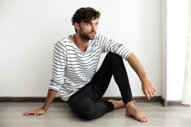 Handsome man in stripes sitting down on the floor - Φωτογραφία, εικόνα