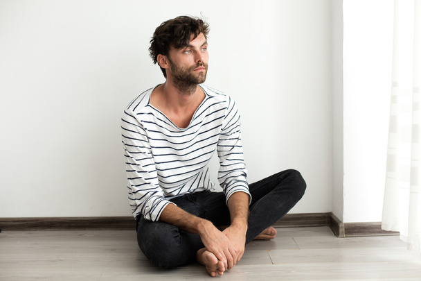 Handsome man in stripes sitting down on the floor - Zdjęcie, obraz