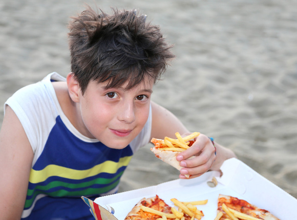 enfant mange une pizza avec des croustilles sur la plage
 - Photo, image