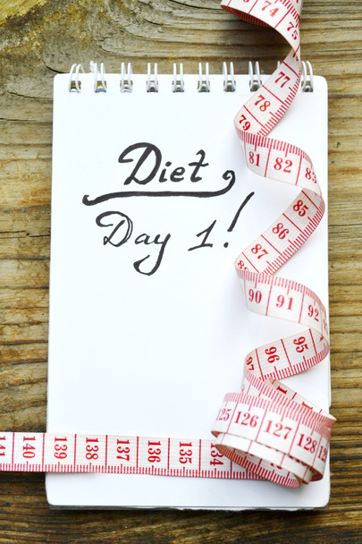 Concepto de dieta con un cuaderno y cinta métrica roja en mesa de madera
 - Foto, imagen