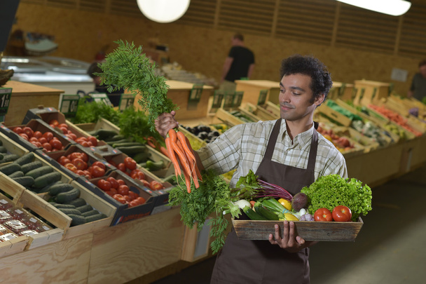 Grocery clerk working in produce aisle of supermarket store - Foto, afbeelding